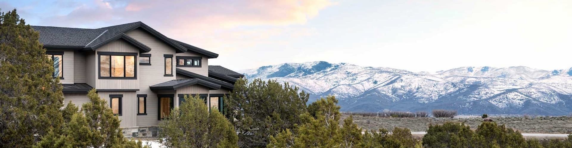 Utah home surrounded by Juniper trees with snowy hills in the background
